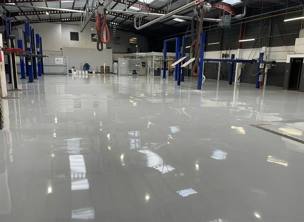 Atelier de maintenance au sol en résine époxy gris brillant, ponts élévateurs bleus