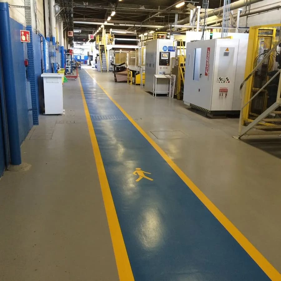 Allée piétonne bleue bordée de jaune, marquée au sol dans un atelier de production