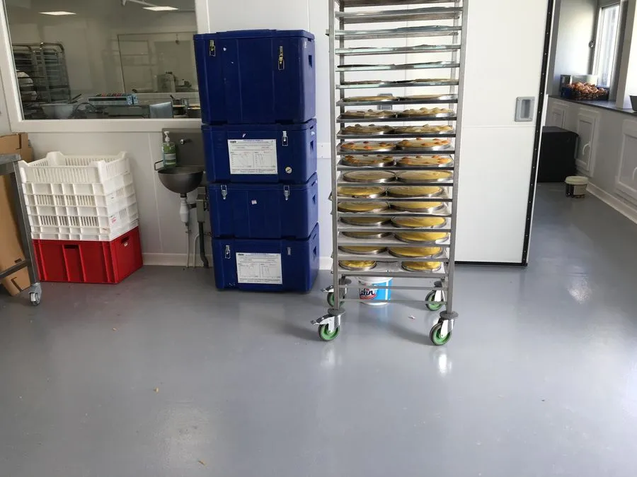 Cuisine professionnelle au sol en résine gris clair, chariot et bacs de stockage