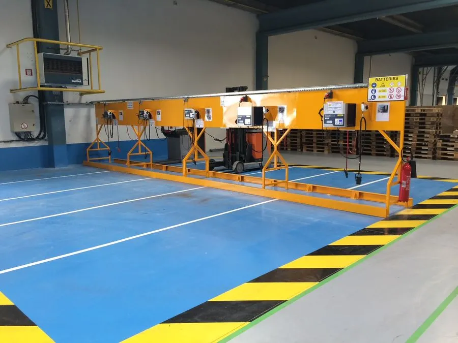 Postes de travail sur un sol en résine bleu, zone délimitée par un marquage jaune et noir