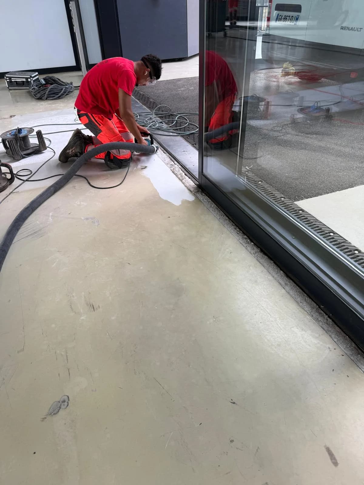 Grenaillage en cours sur une dalle industrielle, grenailleuse reliée à son aspirateur