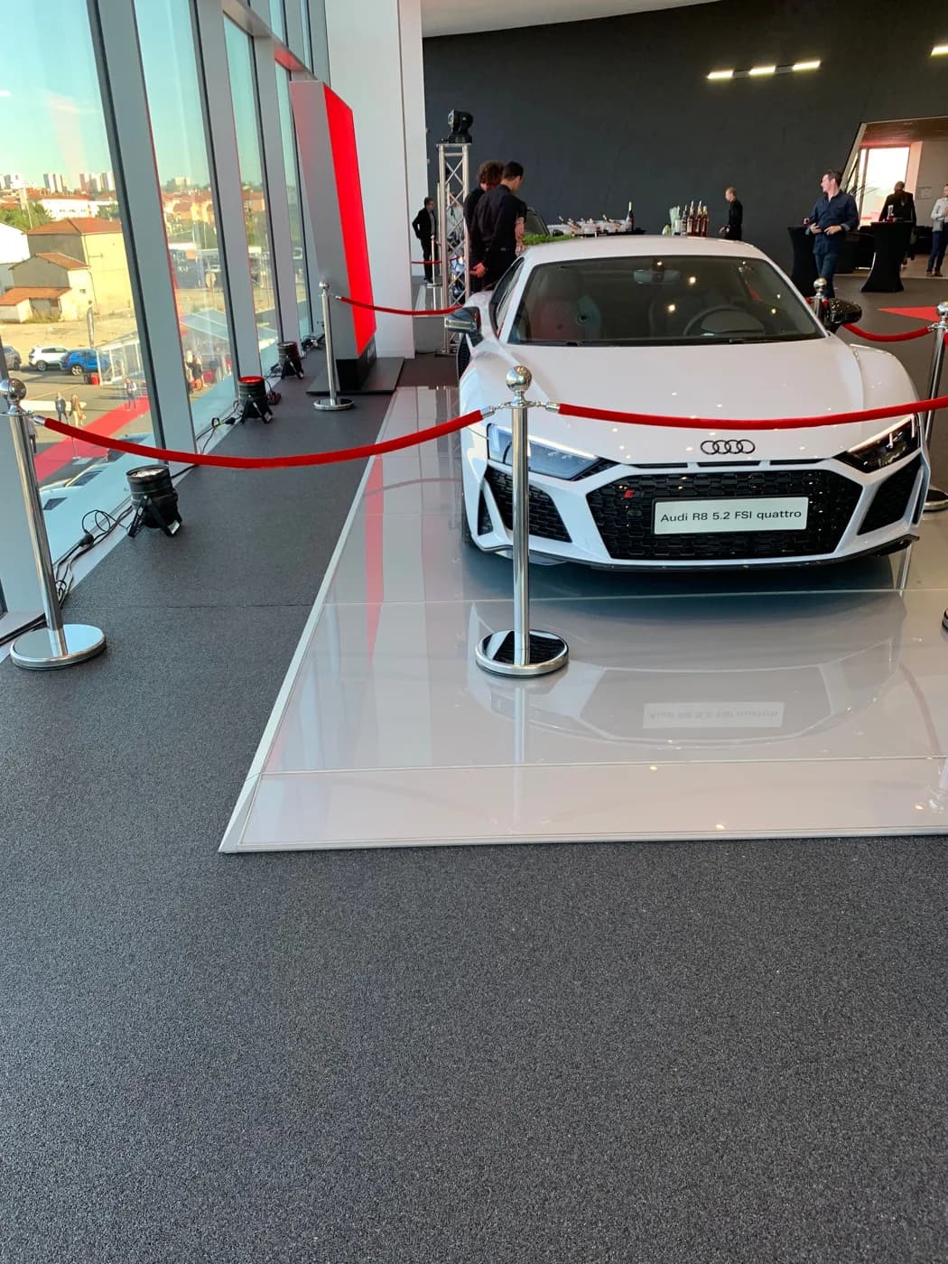 Showroom automobile : sol en résine moucheté et podium clair sous une voiture exposée